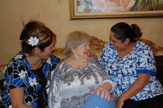 Three women sitting together, smiling and engaged in conversation.
