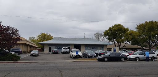 A view of a commercial building with various parked vehicles under a cloudy sky.