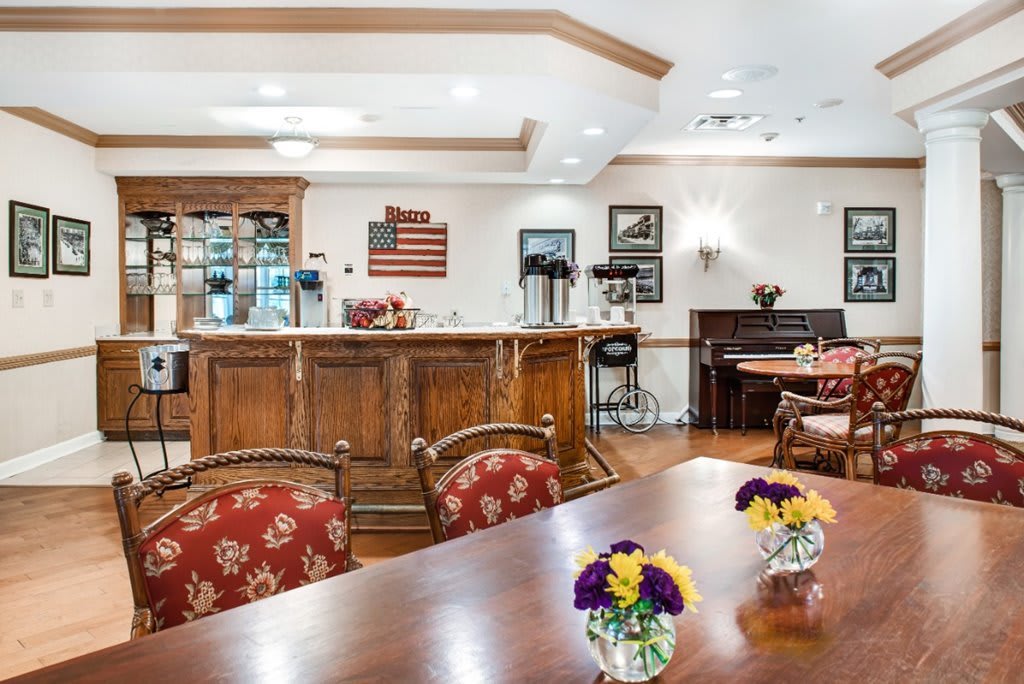 A cozy indoor bar area with wooden furniture, decorated with flowers and American-themed decor.