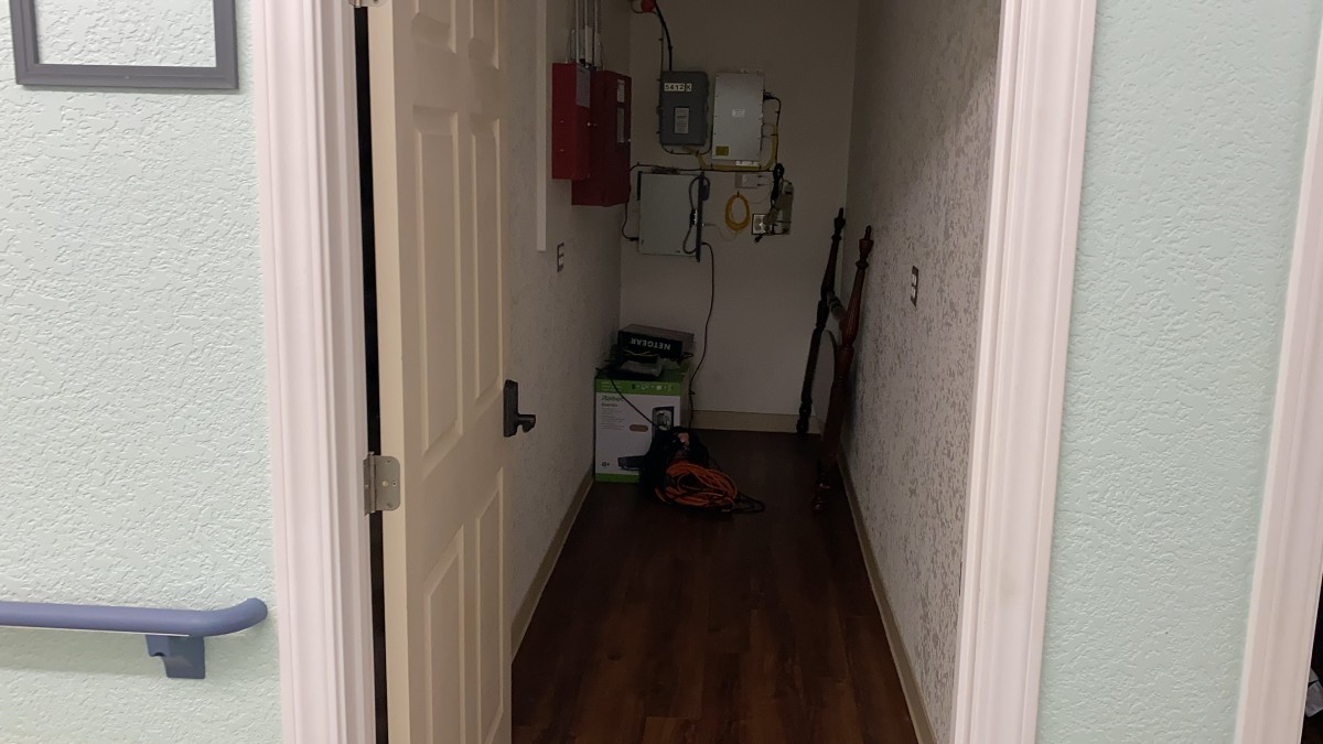 A narrow utility room with tools and equipment visible through an open door.