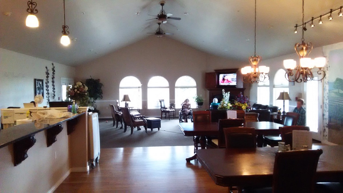 A spacious living room with a dining area, featuring large windows and a television.