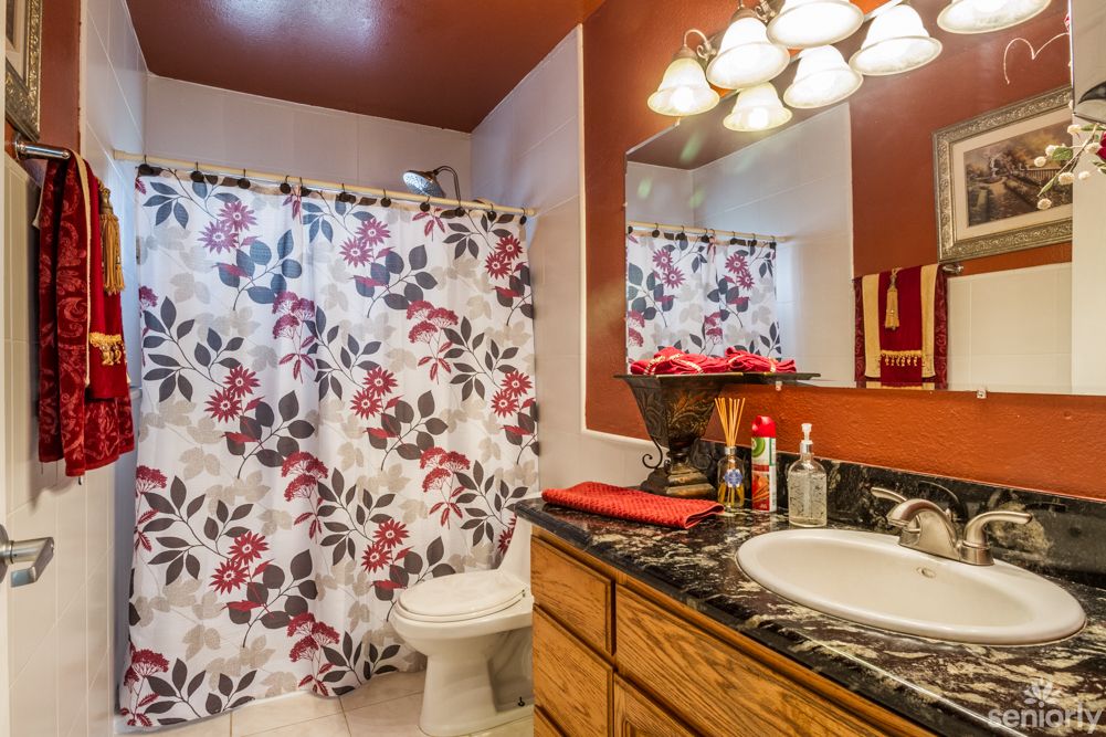 A cozy bathroom with floral shower curtain and warm lighting.