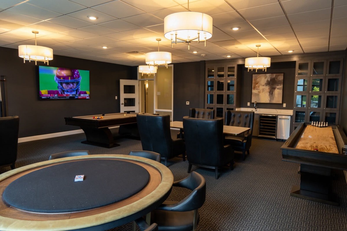 A luxurious game room featuring poker tables, comfortable leather chairs, and elegant chandeliers.