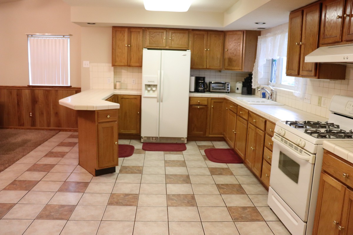 A spacious kitchen with wooden cabinets and tiled flooring.