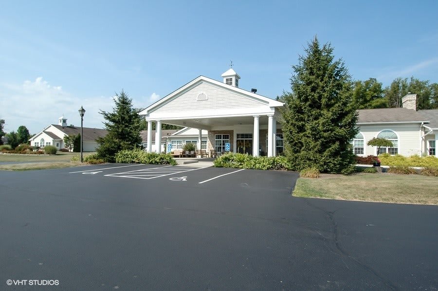 A large building with a pillared entrance surrounded by trees and a parking lot.