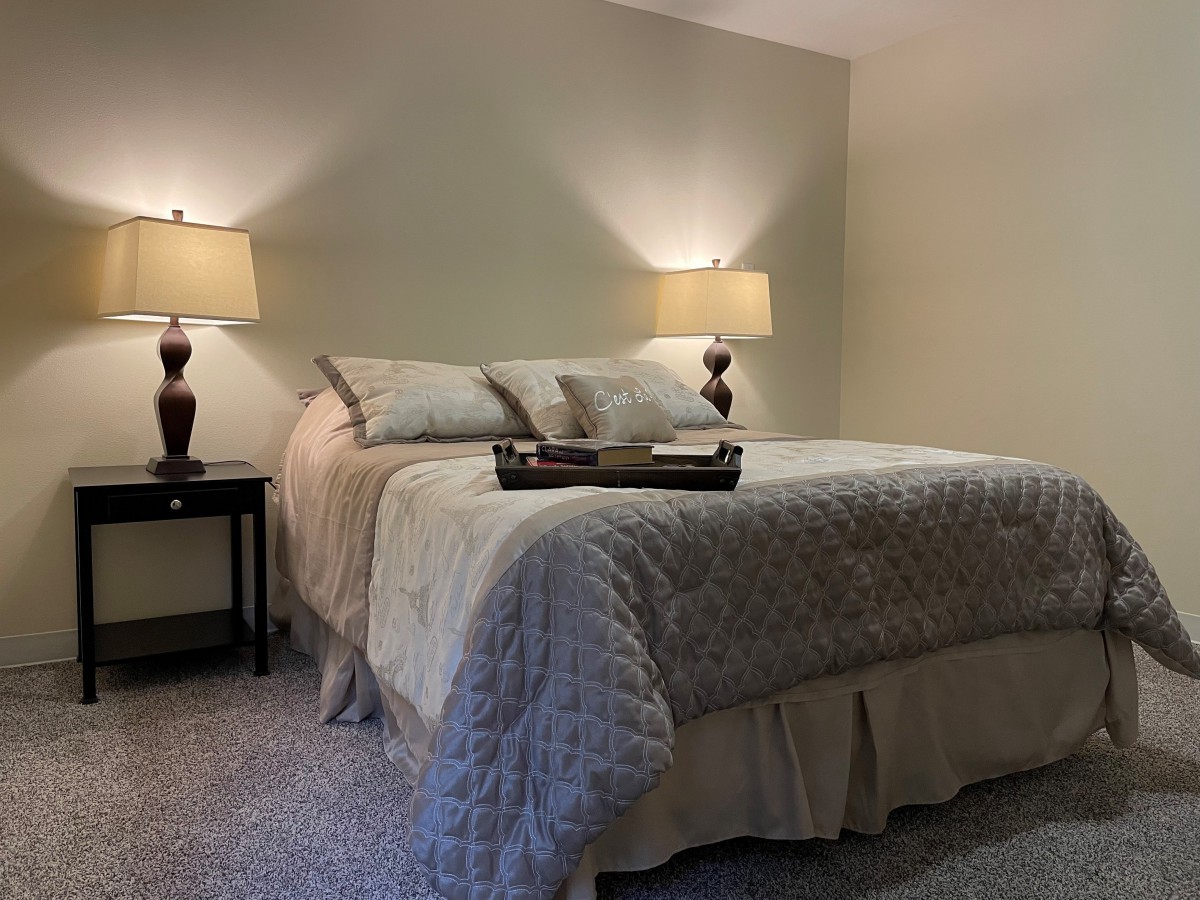 A cozy bedroom with a neatly made bed and warm lighting from two lamps on side tables.