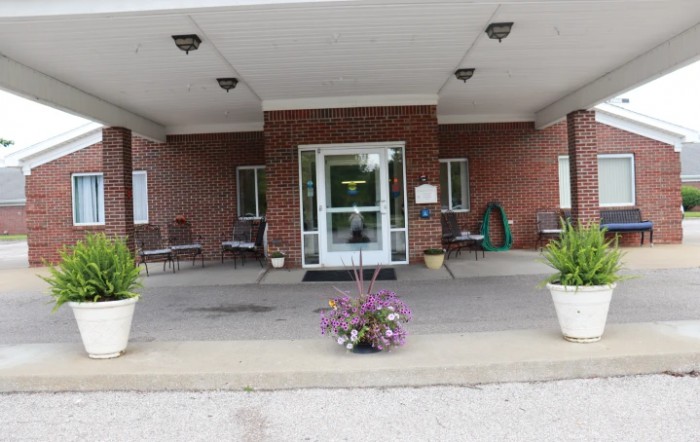Entrance of a building with a covered porch and potted plants.