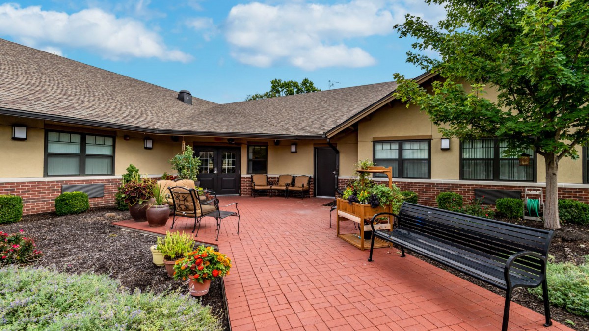 A serene courtyard with benches and potted plants outside a building.