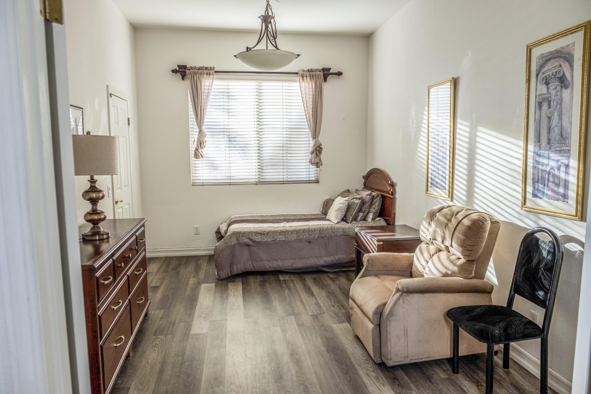 A well-lit bedroom with a bed, comfortable chair, and wooden furniture.