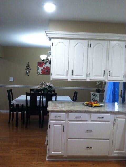 A cozy kitchen with white cabinets and a dining area in the background.