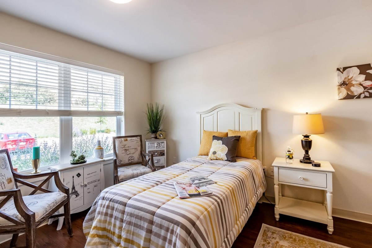 A cozy bedroom with a single bed, decorative accents, and natural light from the window.