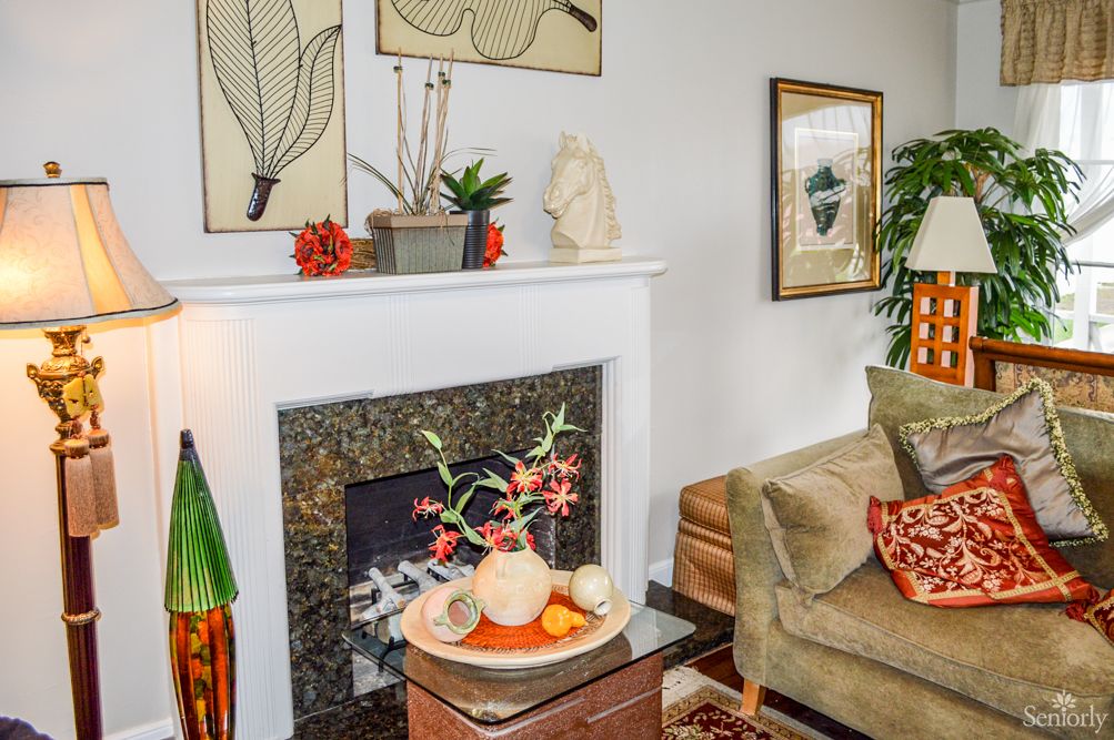 A cozy living room featuring a stylish fireplace, adorned with artwork and plants.