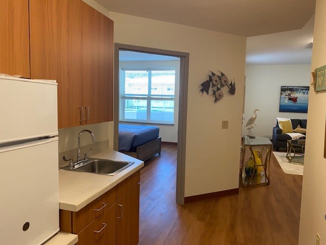 View of an apartment featuring a kitchen area leading to a bedroom with wooden flooring.