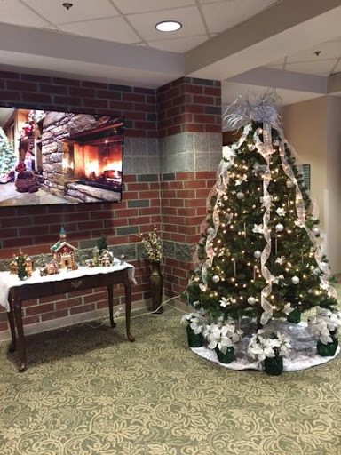 A beautifully decorated Christmas tree with festive ornaments and a cozy fireplace displayed on the TV in a warmly decorated interior.