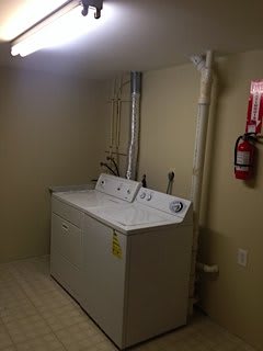 A basement laundry room with a washer and dryer set along the wall.