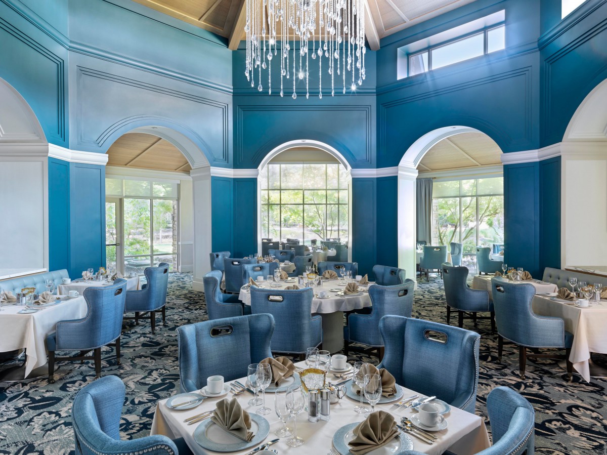A luxurious dining room with elegant blue decor and a grand chandelier.