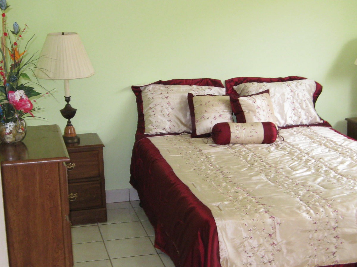 A cozy bedroom with a neatly made bed, featuring elegant bedding and decorative pillows.