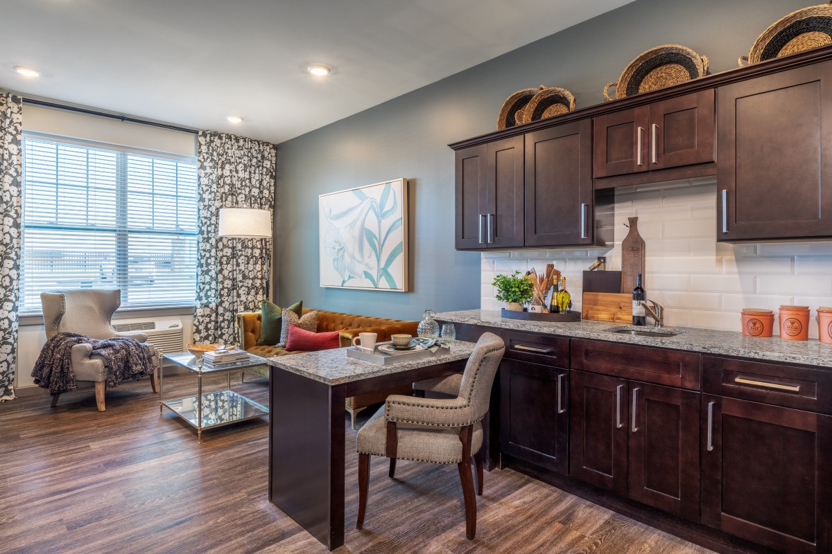 A beautifully designed living room with a cozy home office setup, featuring modern furniture and wooden flooring.