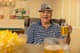 A man wearing a hat sits at a table with drinks in a restaurant.