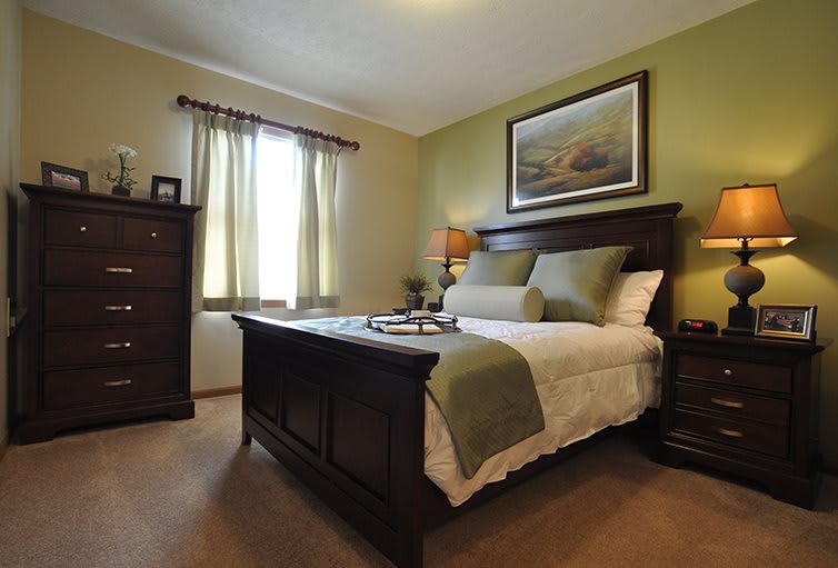 A cozy bedroom with green tones and elegant decor.