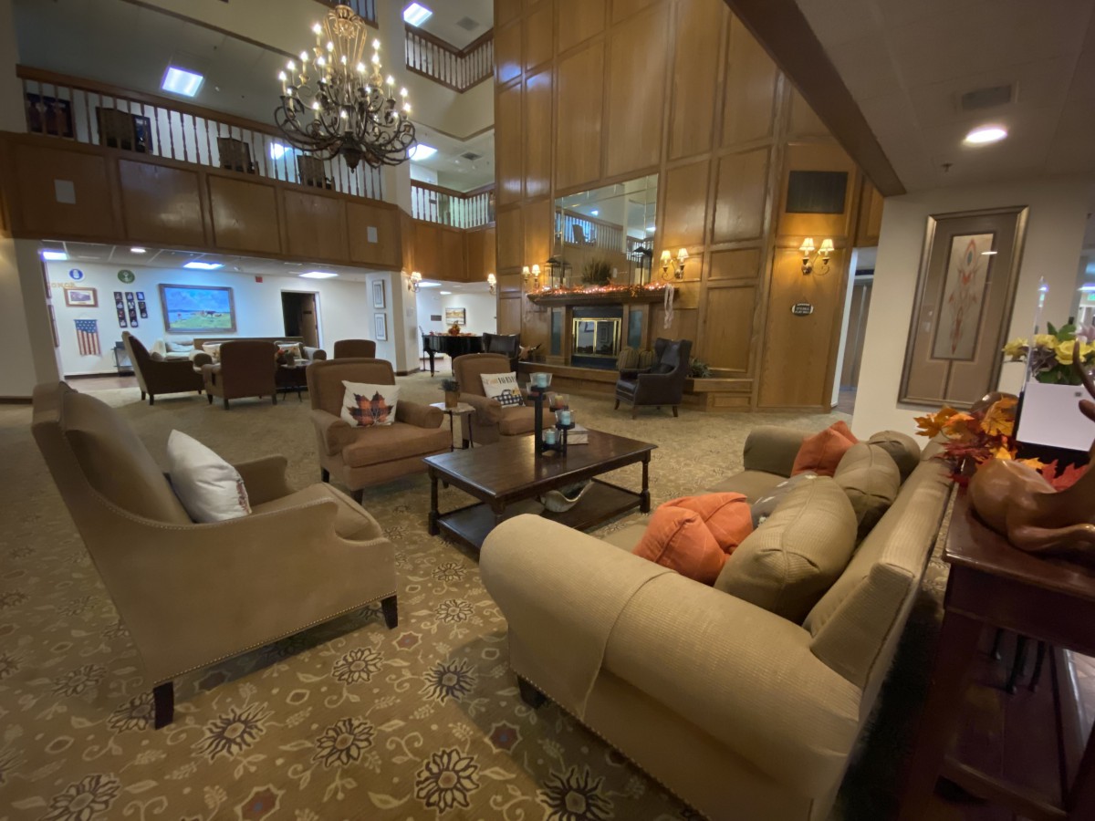 A spacious and elegantly decorated lobby featuring comfortable sofas, a large chandelier, and classic wood paneling.