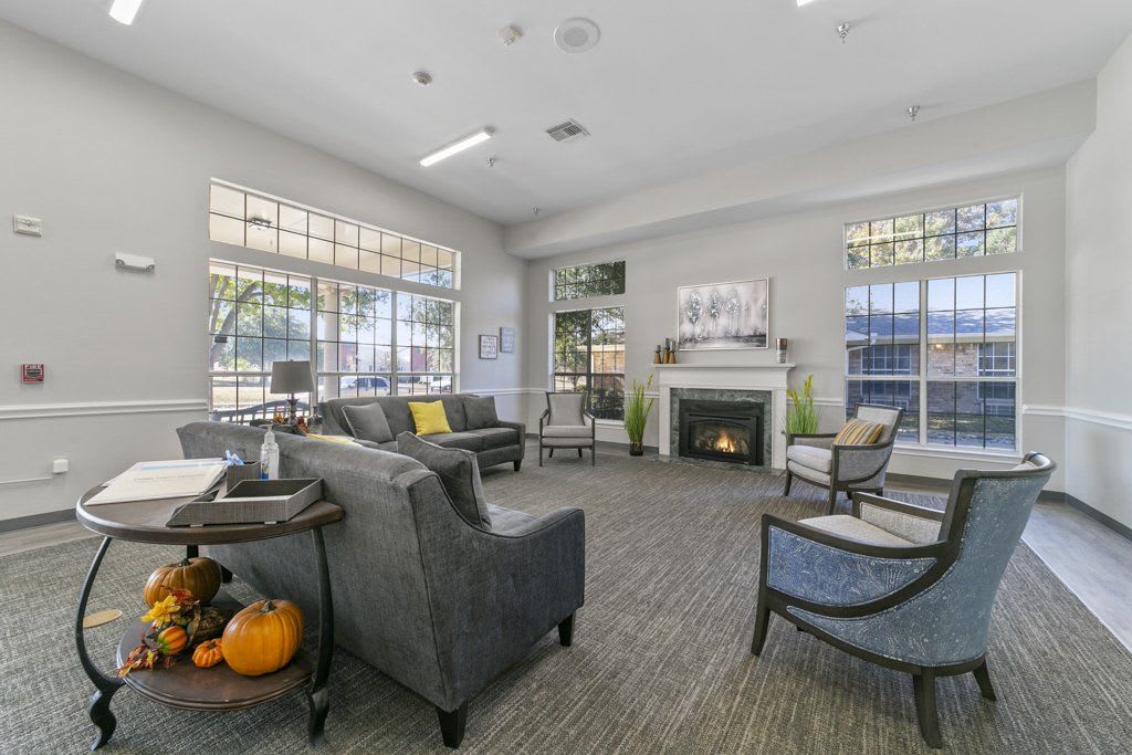 A modern living room with comfortable seating, a fireplace, and decorative pumpkins.