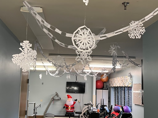 A festive gym space adorned with stylish holiday decorations, including paper snowflakes and a Santa figure.