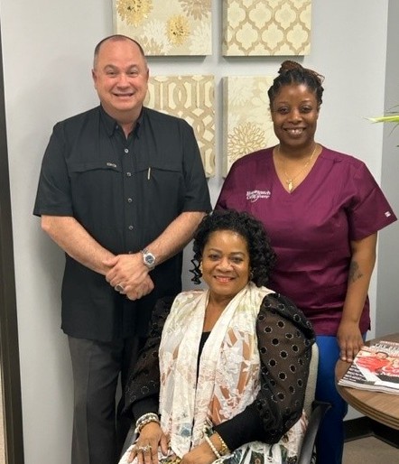 A group photo of three smiling individuals in an office setting.