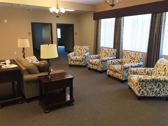 A cozy living room with patterned chairs and a sofa arranged around a central table.