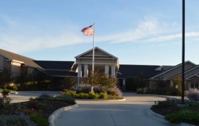 A building with an American flag flying in front of it, set against a clear sky.
