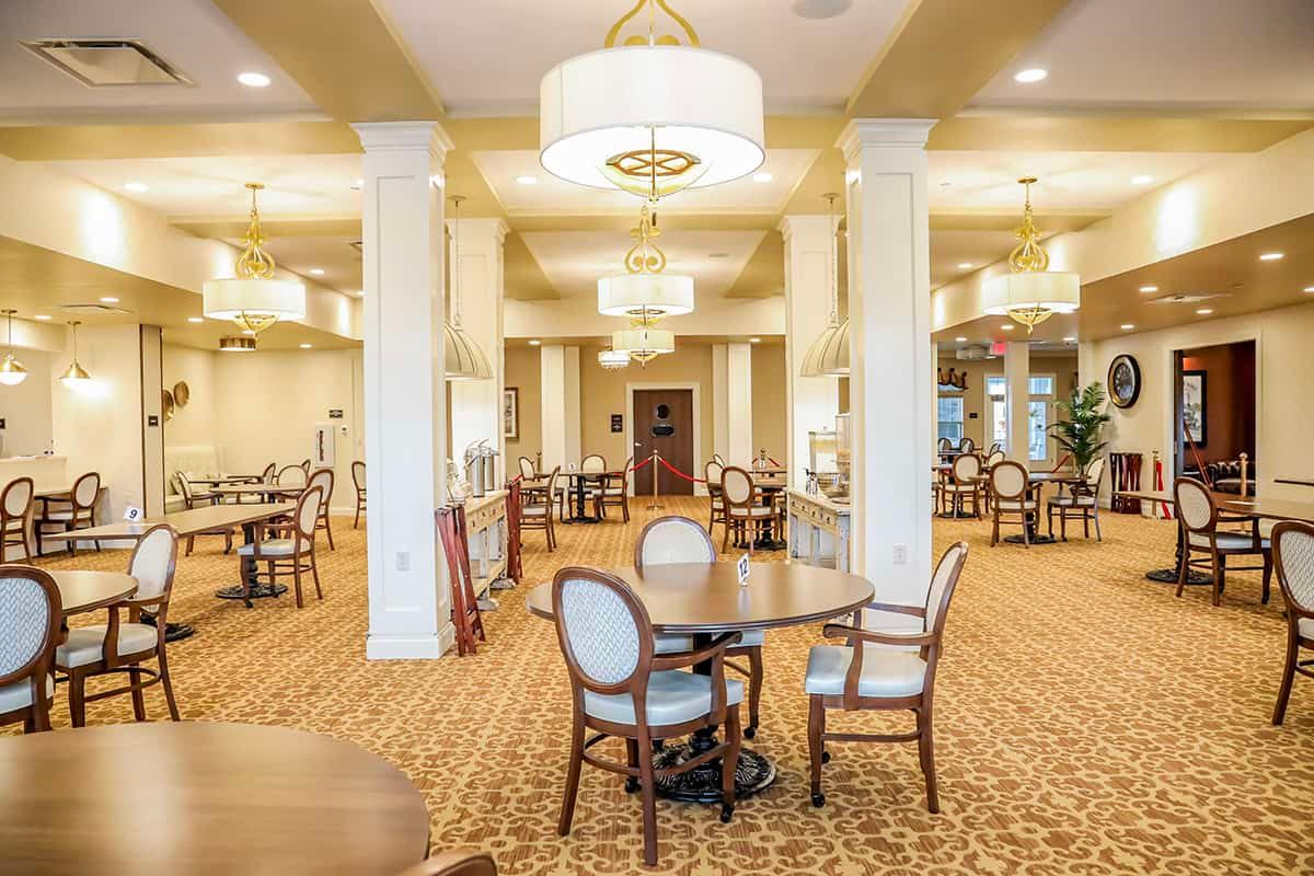 A spacious dining area with elegant chandeliers and neatly arranged tables and chairs.