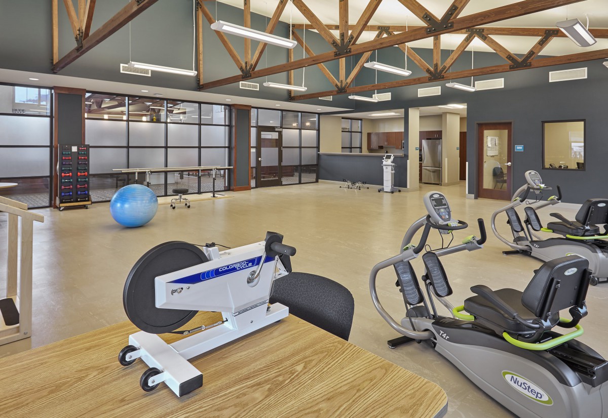 A spacious gym with various exercise equipment and a modern design.