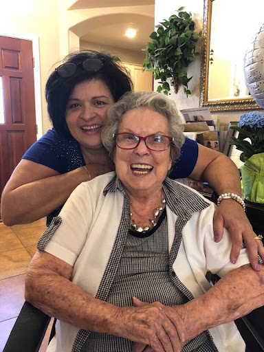 A joyful moment shared between a younger woman and an elderly lady, both smiling brightly.