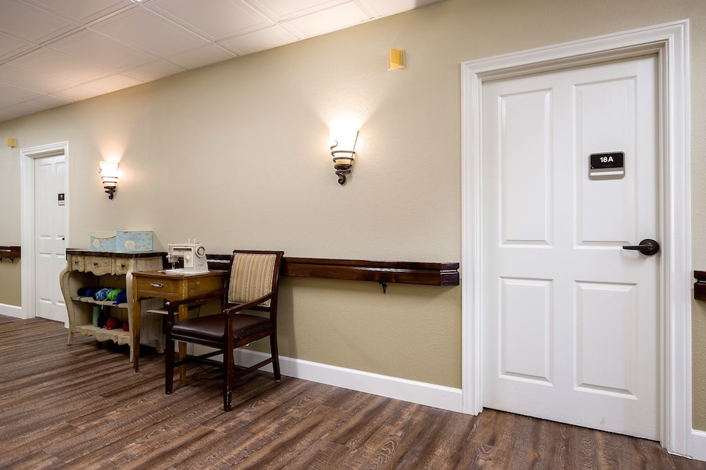 A quiet room featuring a wooden chair and table against a beige wall with decorative lighting.