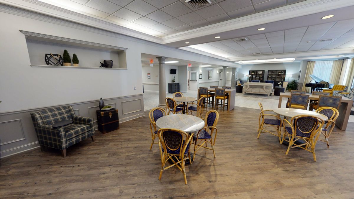 A spacious and modern cafe interior with tables and chairs, featuring a wooden floor and bright lighting.