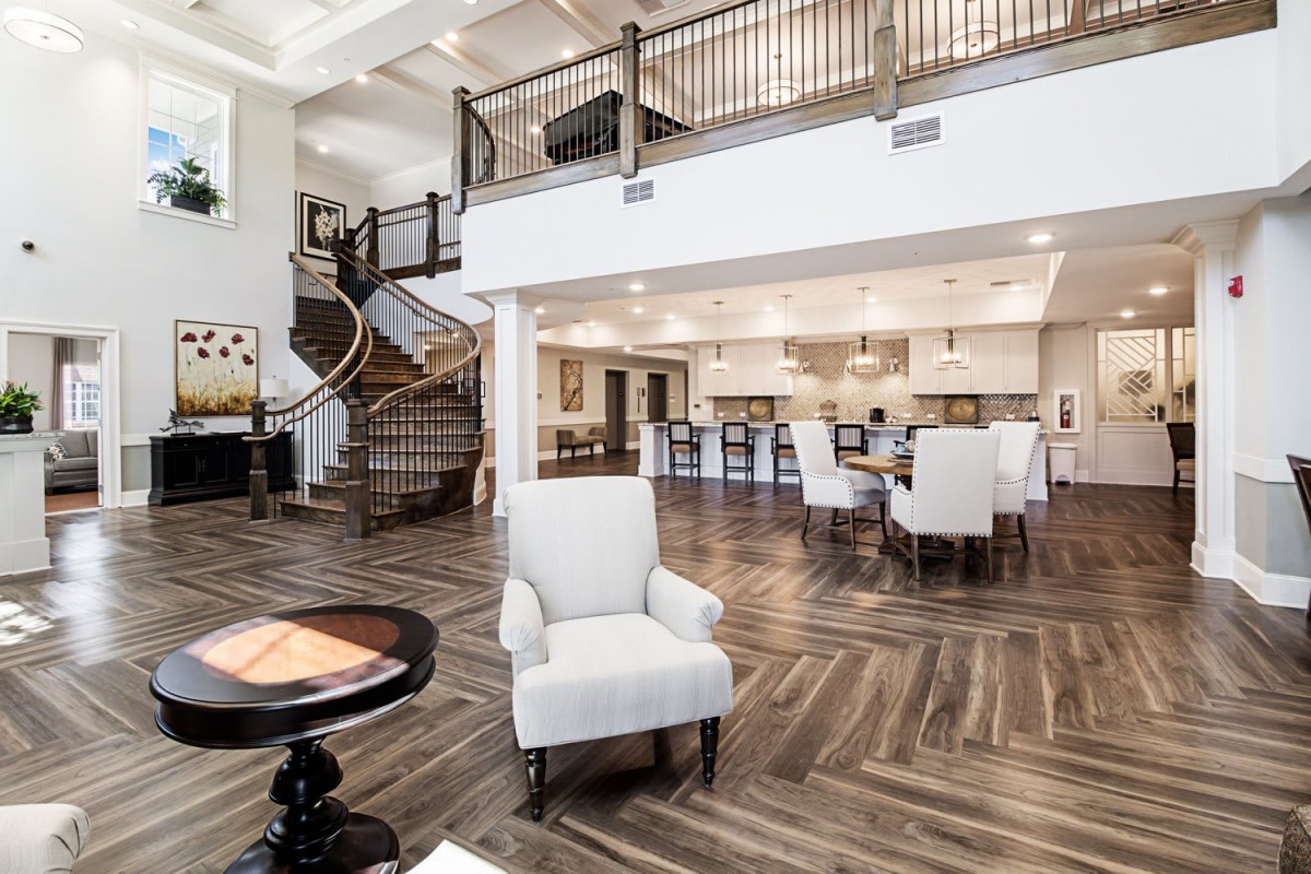 A spacious open-concept interior with modern design, featuring a living area, dining space, and kitchen with a prominent staircase.