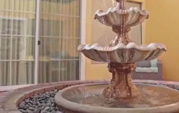 A decorative outdoor stone fountain with water gently cascading from tier to tier.
