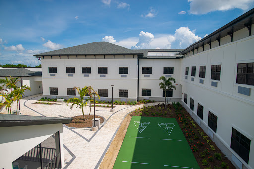 A modern building with a landscaped courtyard featuring palm trees and an open sky.
