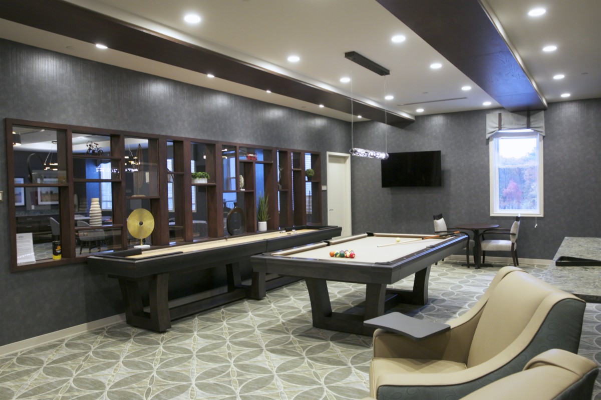 A modern game room featuring a pool table and lounge seating with a television mounted on the wall.