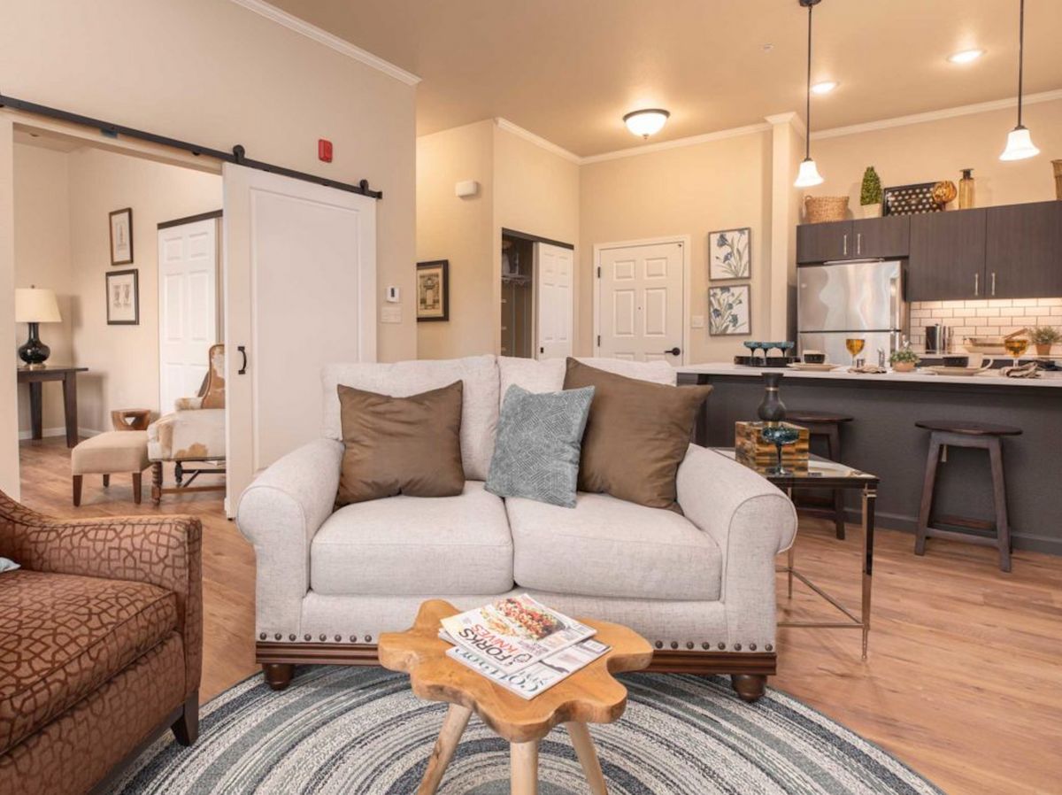 A cozy living room with a comfortable sofa and modern decor, featuring an open kitchen layout.