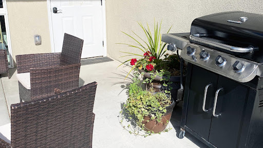 A cozy outdoor patio setup featuring a barbecue grill and vibrant flower planters.