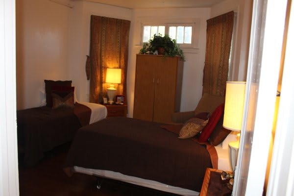 A cozy bedroom with warm lighting, featuring a bed, wardrobe, and lamps.