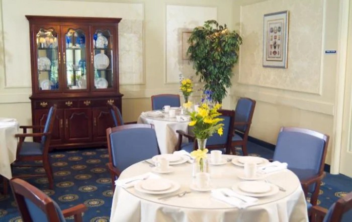 An elegant dining room with neatly set tables, upholstered chairs, and a decorative china cabinet.