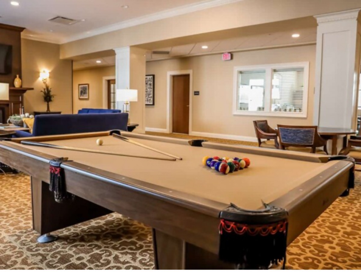 A stylish game room featuring a neatly set pool table with billiard balls and cue sticks.