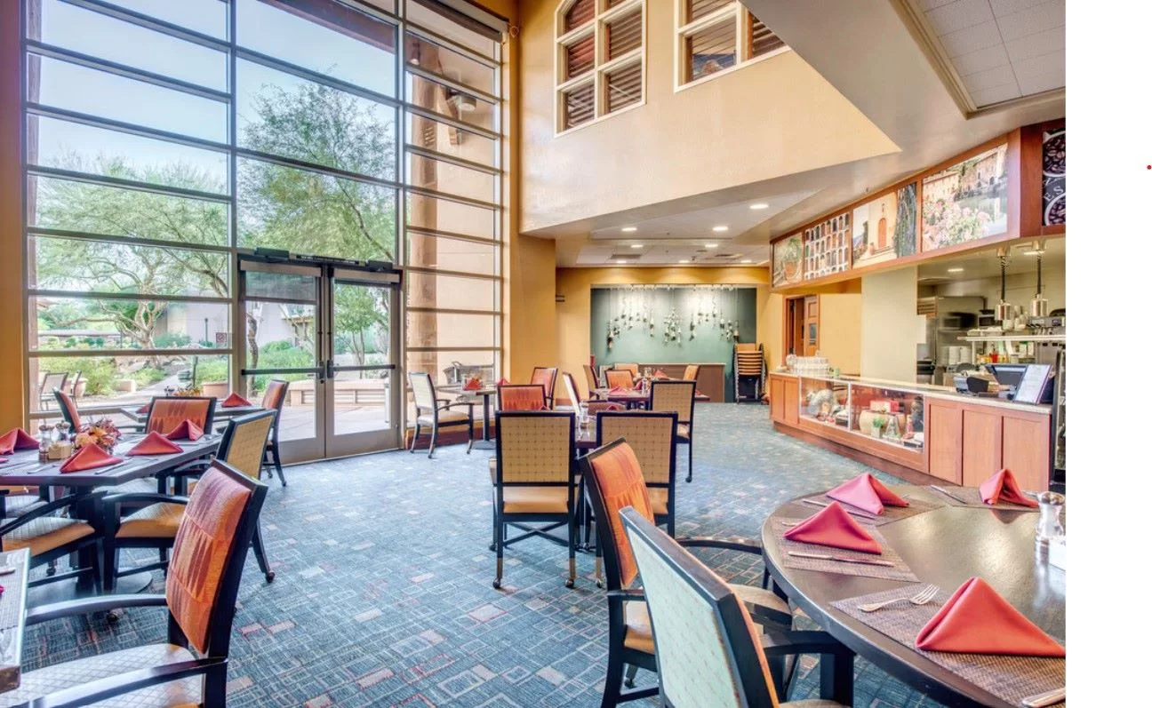 A modern restaurant interior with large windows, natural lighting, and neatly arranged tables.
