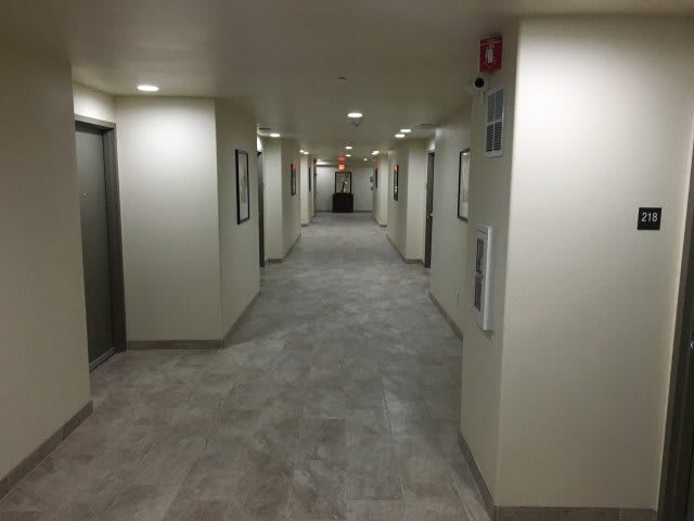 A view down a well-lit, modern hallway with multiple elevators and doors.