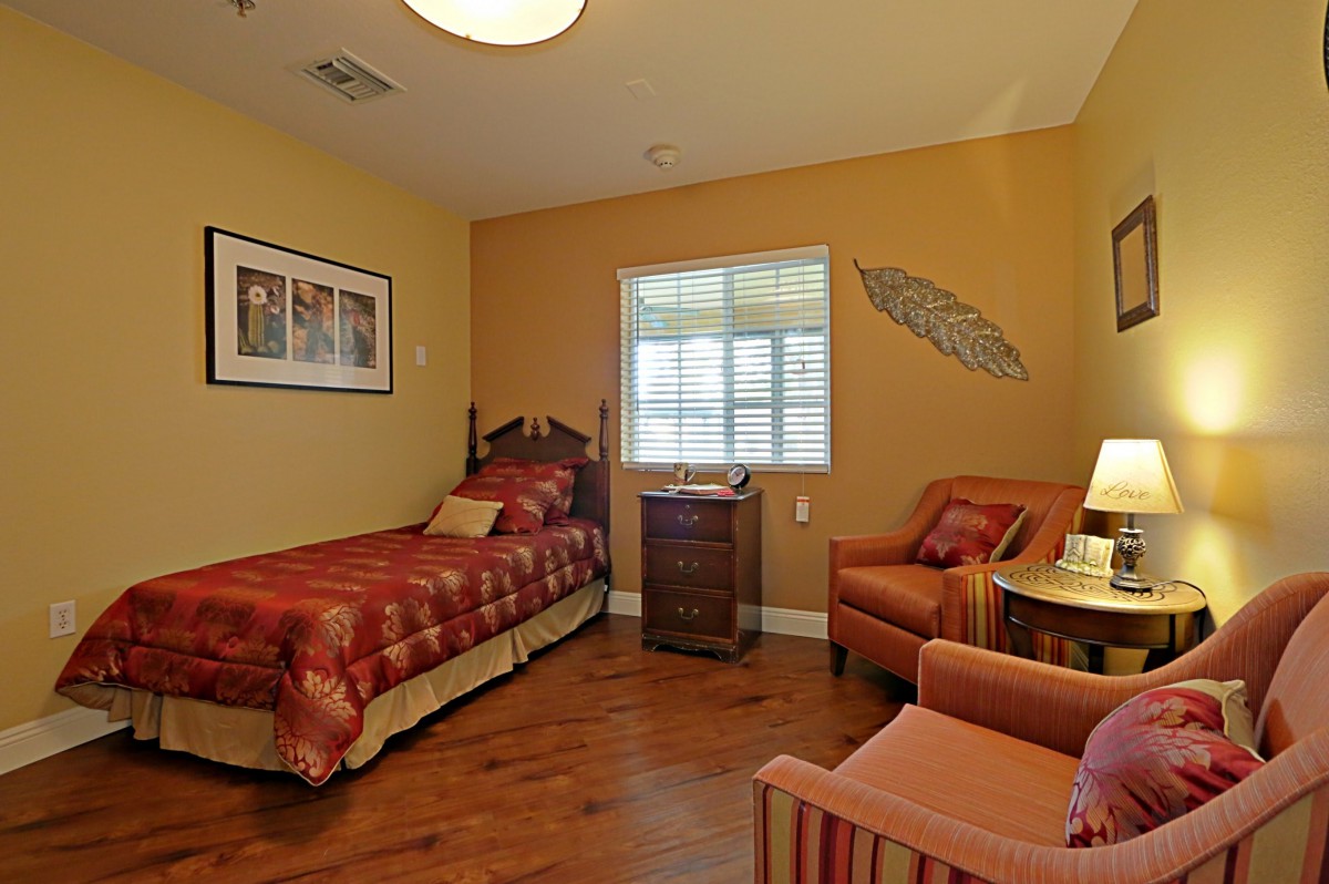 A cozy bedroom with a single bed, armchair, and wall decor.