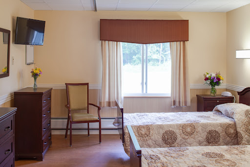 A cozy hotel room featuring a bed, a chair, a TV, and a view through the window.