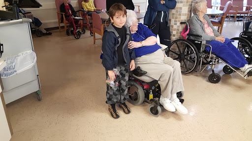 A young child sharing a tender moment with an elderly woman in a care facility.