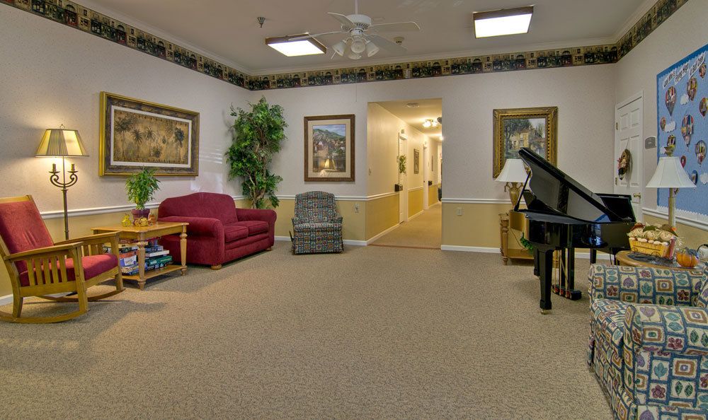 A cozy living room with comfortable seating, framed artwork, and a piano.